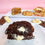 Thumbnail: Cookies & Cream Gluten Free NYC Cookies in half with other cookies in the background