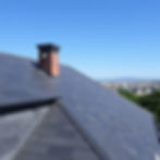 An elevated view of a meticulously installed premium slate roof featuring a brick chimney, showcasing the specialized, delicate handling of high-end slate, clay tile, and wood shake installations by Central Roofing Inc. in San Francisco.