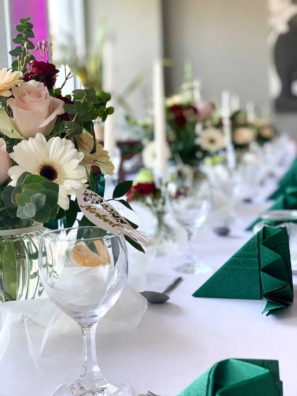 Detailaufnahme von zarten Blumenarrangements auf einem Veranstaltungstisch.