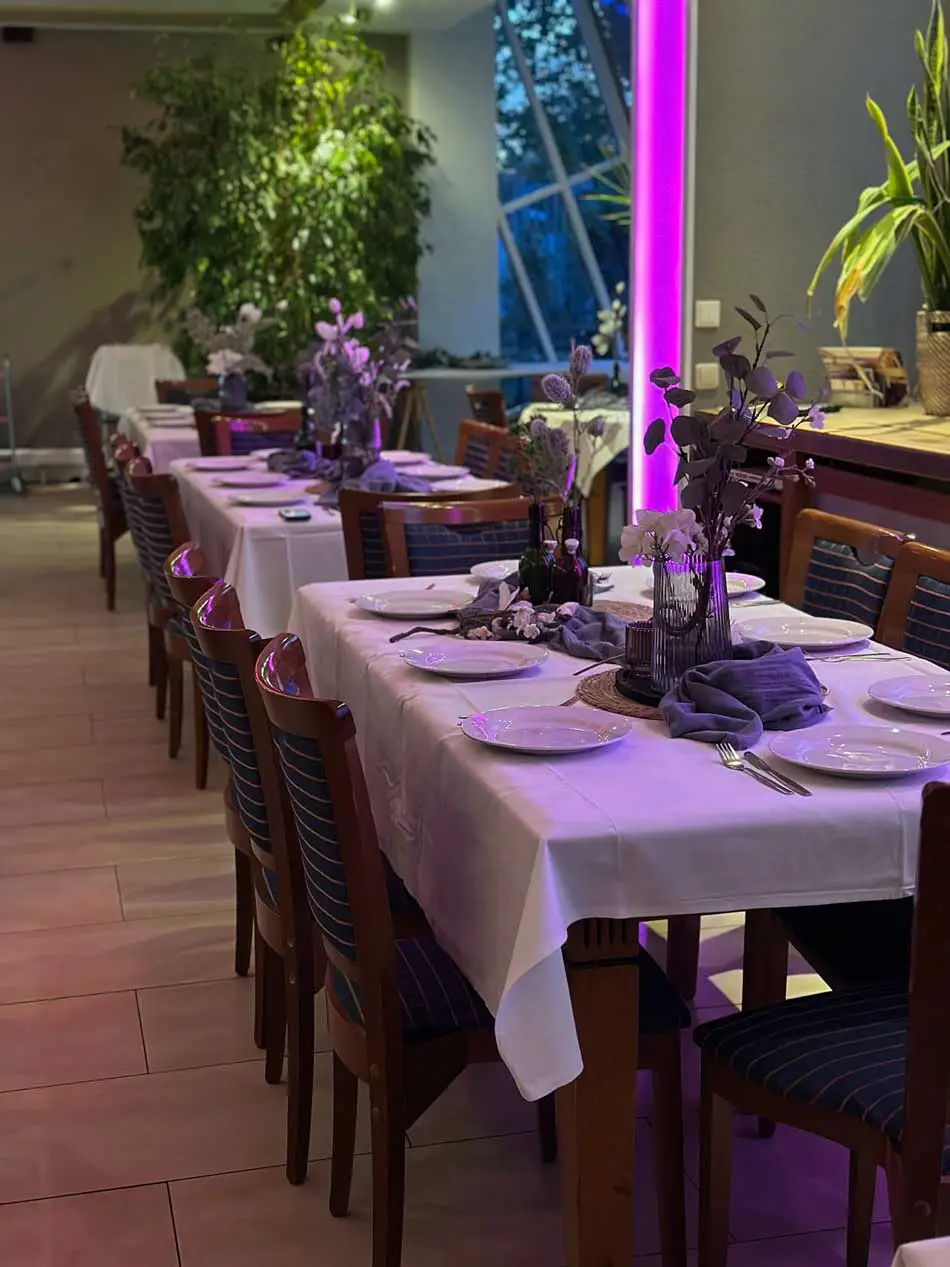 Elegant gedeckte Tische in einer stilvoll beleuchteten Eventlocation mit lila Akzenten.