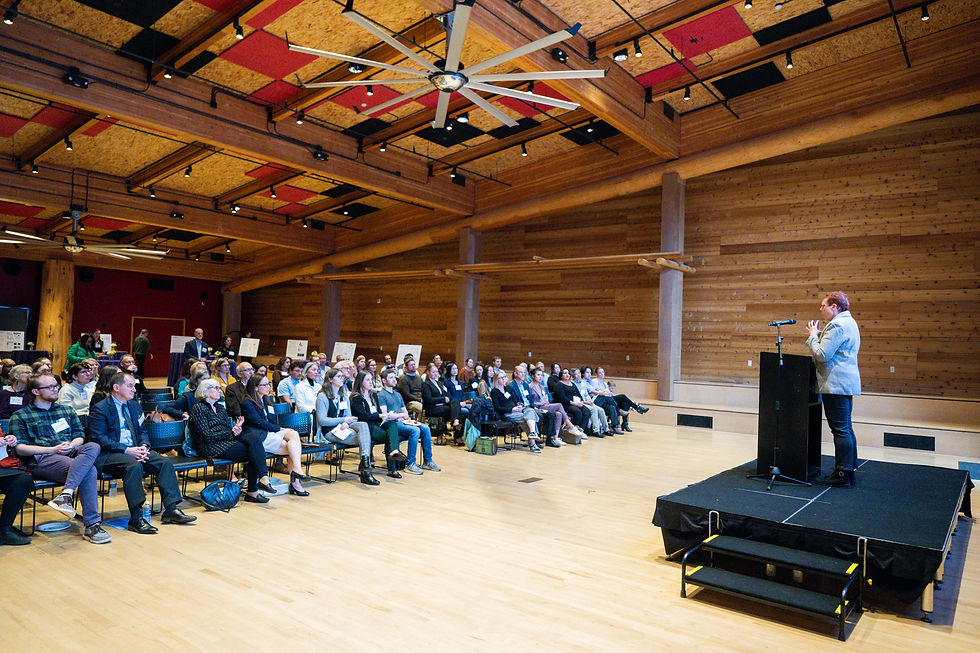 Nora Disis stands at a podium and stage in front of an audience.