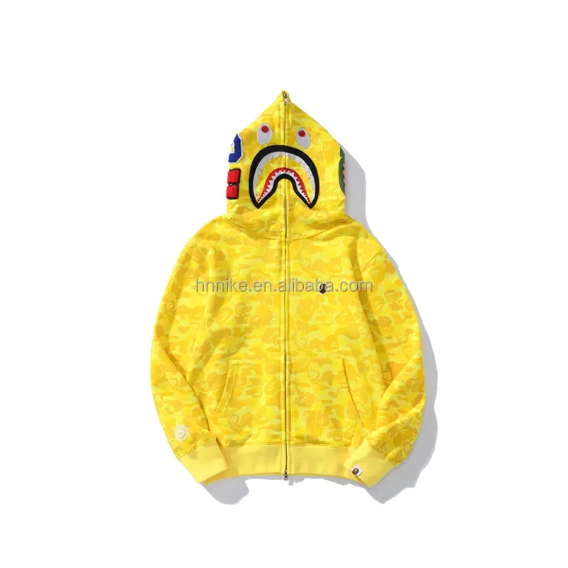 Thumbnail: Yellow BAPE hoodie with shark mouth design, online retailer logo, and zipper closure.