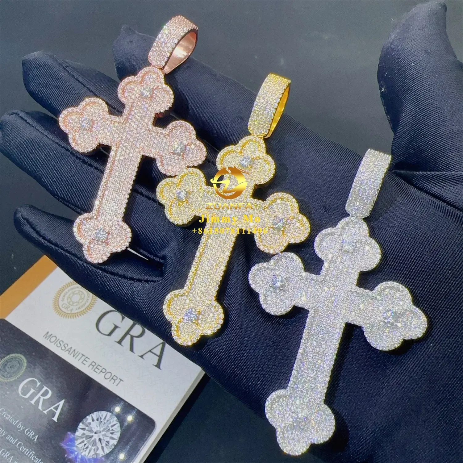 Three diamond-encrusted cross pendants held by hand with GRA certificate in view.