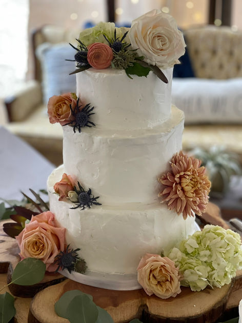 Rustic buttercream wedding cake decorated with fresh flowers and natural accents for an elegant celebration.