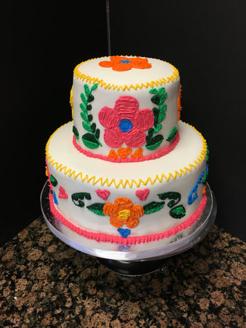 Colorful folk art-inspired tiered celebration cake featuring handcrafted floral decorations.