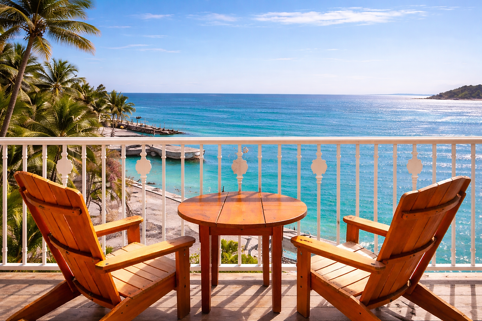 Two wooden chairs and a round table beckon on a balcony, offering a serene view of the turquoise harbor waters and swaying palm trees.
