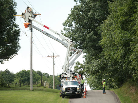 Bucket truck on a rural road, crew working on aerial cable, utility poles. Michael Wilson, Unsplash.