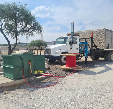 "Trabajadores de Constructora Grupo JAC realizando instalación de cableado eléctrico en una nave industrial."