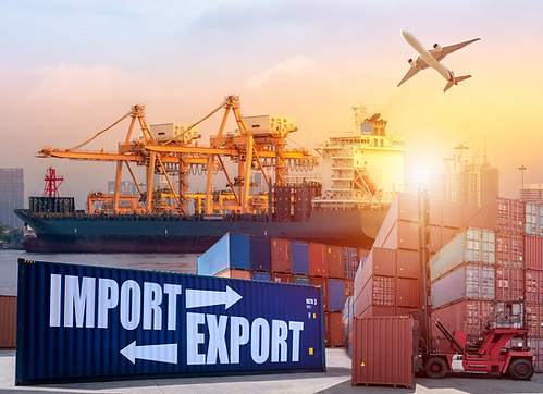Container Cargo freight ship with working crane bridge in shipyard at sunrise for Logistic