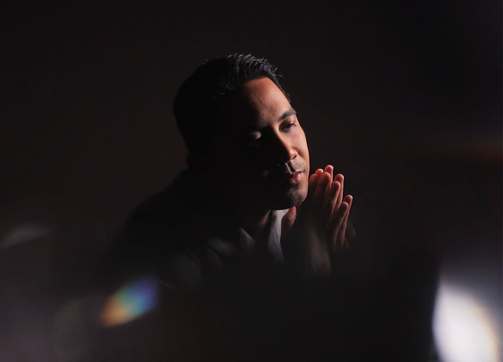 Hafiz Hamidun in a dark setting, hands together, looking thoughtful.