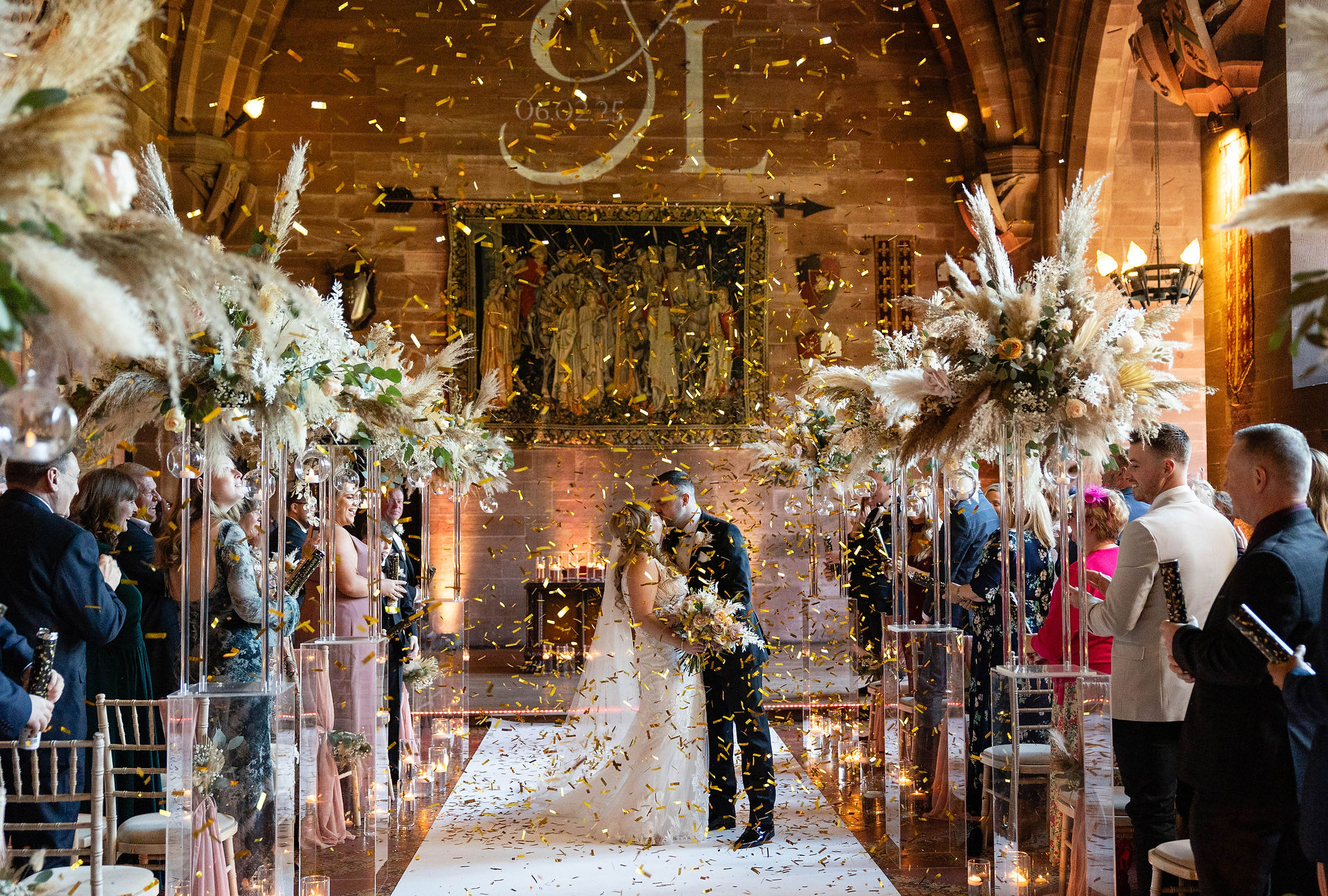 Bride and Groom kissing in the ceremony room at Peckforton Castle while being covered in confetti. Taken by Nicki Jones Photography, Shropshire Wedding Photographer.