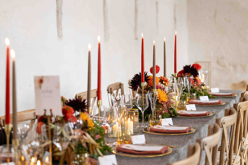 Elegant table setting with red and beige candles, autumn flowers, and name cards at The Courtyard Venue in Oswestry. Warm, inviting mood in a rustic room.