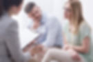 Upset young woman talking to a female psychologist, with her husband aside.jpg