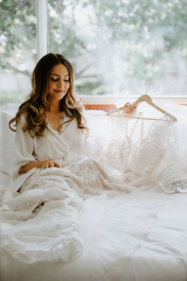 A bride looking at her wedding dress after bridal hair and makeup completed by Brooklin Mane Whitby