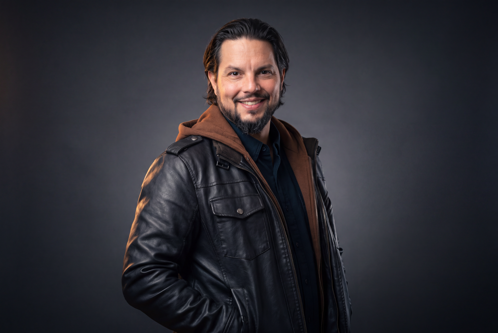 Richard Langberg smiling in a black leather jacket and brown hood