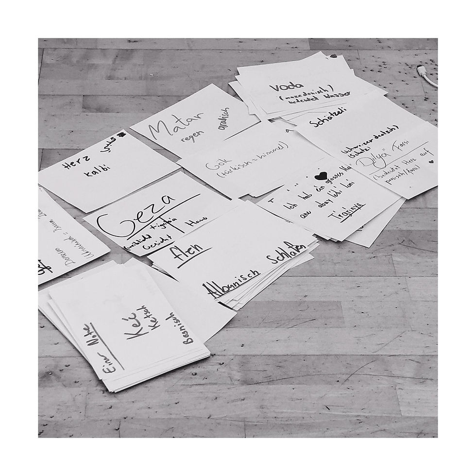 Auf dem Boden liegen beschriebene Zettel mit Wörtern aus anderen Sprachen.