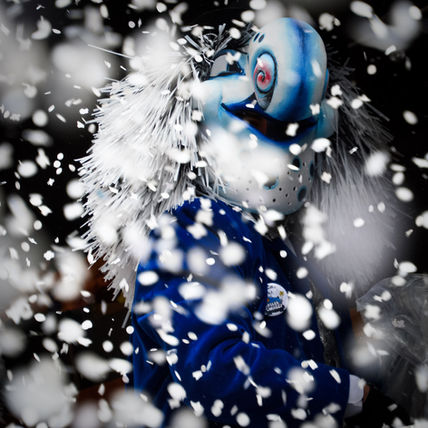 Waggis at Basel Fasnacht throwing white confetti, making it look like snow is falling in the street.