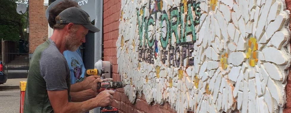 Volunteers work together to add flower petals to Victoria's mural