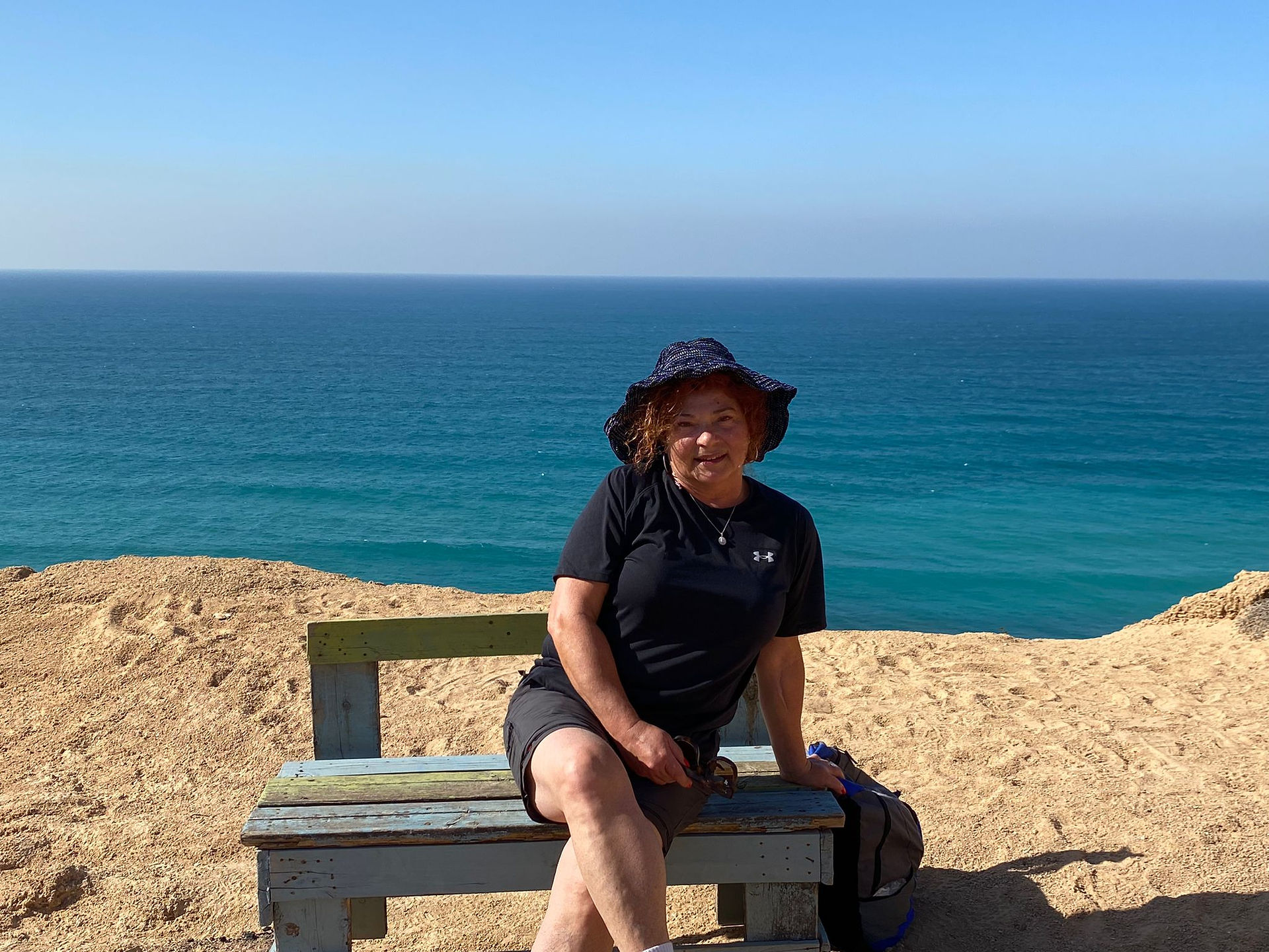 אישה על ספסל על רקע הים