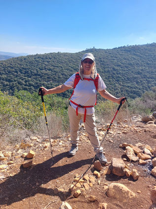 מטיילת עם מקלות הליכה מחייכת למצלמה