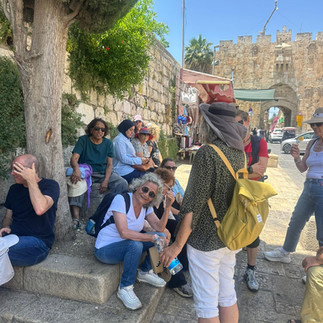 אישה עם תיק גב צהוב ואישה יושבת עם חולצה לבנה
