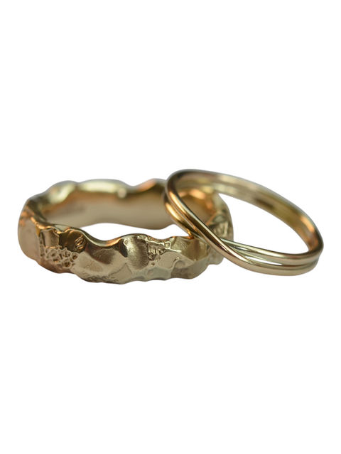 Mismatching wedding bands for him and her both in 9 carat gold - hers in made form a thin gold wire and double wrapped, his is a chunky uneven, almost earthy, band