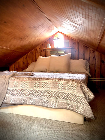 bed in cottage loft bedroom, cozy small space, before window a/c unit is removed