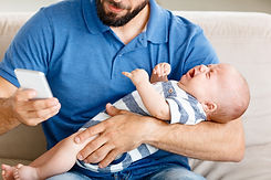 Dad holding a crying baby, texting his virtual doula for support