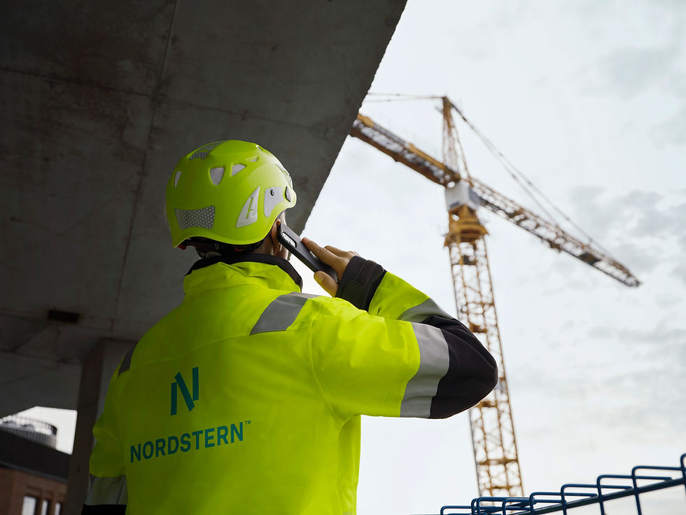 Nordstern worker in high-visibility gear talking on phone near a crane.