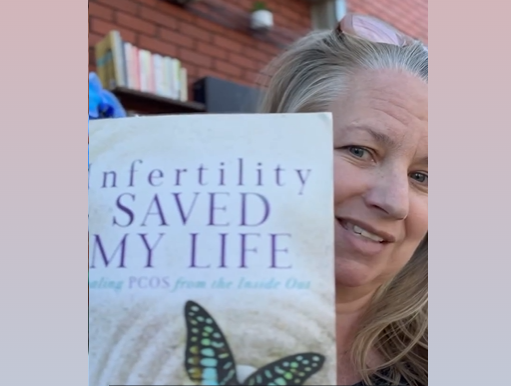 A lady holding a copy of the book Infertility Saved My Life: Healing PCOS from the Inside Out by Sarah Willoughby