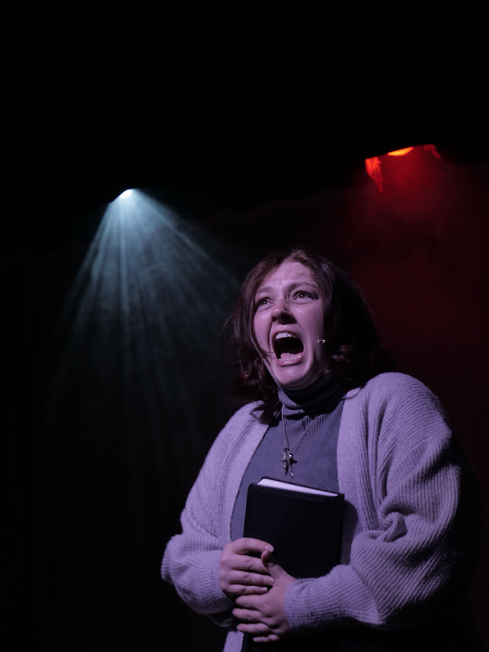 A woman singing angrily clutching a bible to her chest