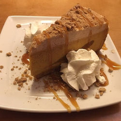 Pumpkin Cheesecake - topped with caramel sauce and ginger cookie crumbles. Served with whipped cream