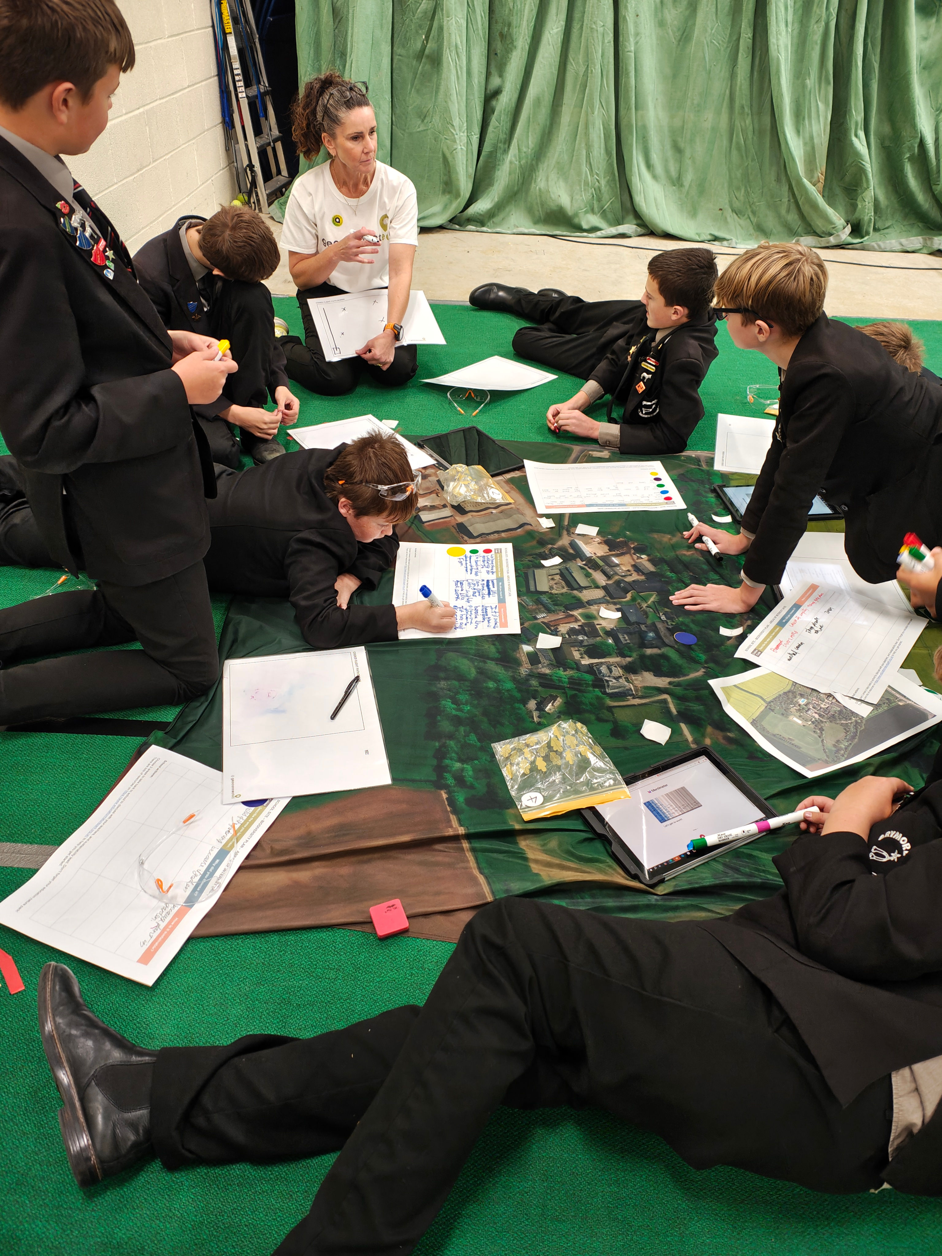 children sitting around a satellite image map on the floor