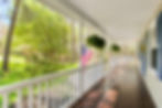 White, wide front porch with an American flag