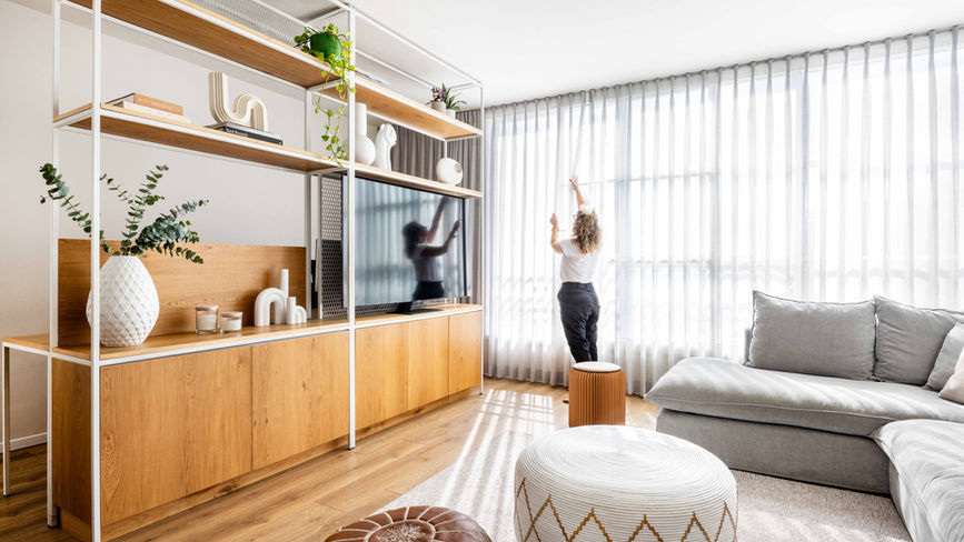 אישה מסדרת וילון בחדר אור מודרני