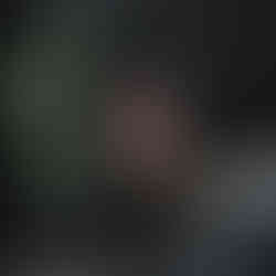 Minimalist illustration of a black bear sitting on snowy hills with bare trees and a large red sun in the sky.