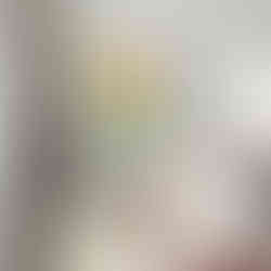 Woman in yellow hat and coat sitting on a pink and blue bench with tropical leaves and a pink background.