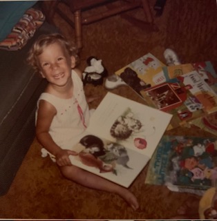 A young Stacey beams up amongst a spread of books.