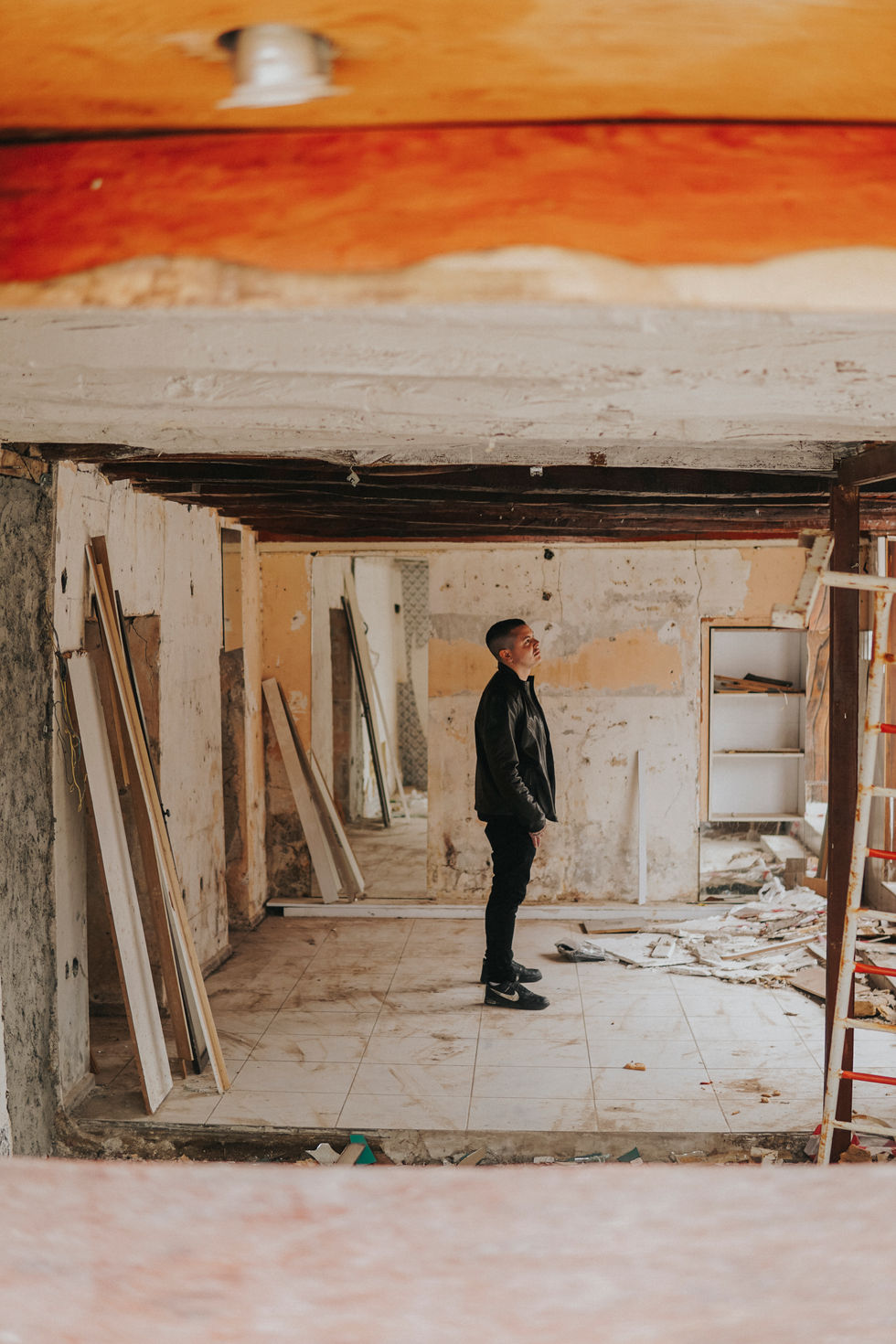 Lukas Makeswaran stands in a room under construction, looking up at the ceiling.