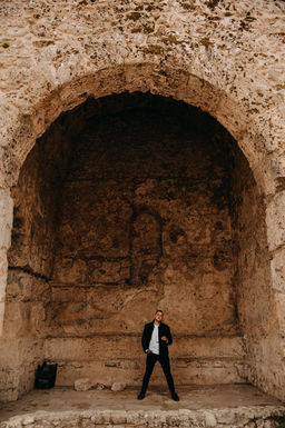 Lukas Makeswaran posing under a stone archway, dressed in black.