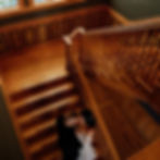 A couple on the historic wooden staircase inside The Broz Event Venue, seen from above