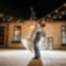 Newlyweds dancing under string lights on the brick patio at The Broz Event Venue at night