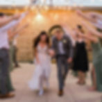 Newlyweds walking through a tunnel of cheering guests at The Broz Event Venue