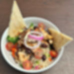 Grilled chicken bowl with tomatoes, olives, and pita bread.
