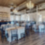 The Grand Ballroom at The Broz Event Venue set for a wedding reception with round tables, Chiavari chairs and chandeliers