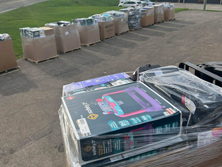 Freshly wrapped liquidation pallets lined up outside Liquidation Land on a sunny day in Grandville, MI, ready for resellers and bargain hunters.