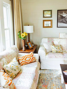 Cozy living room with floral patterned couches, lamp and decorative pillows.