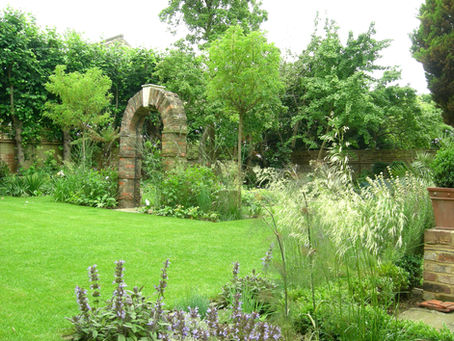 A garden with brick archway, lawn and planting