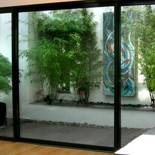 View through big glass windows to a small Japanese style garden with Acer and bamboo 