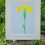 Thumbnail: Iris wall art of a yellow flag iris flower against a pale blue background, in a white frame in front of green garden leaves